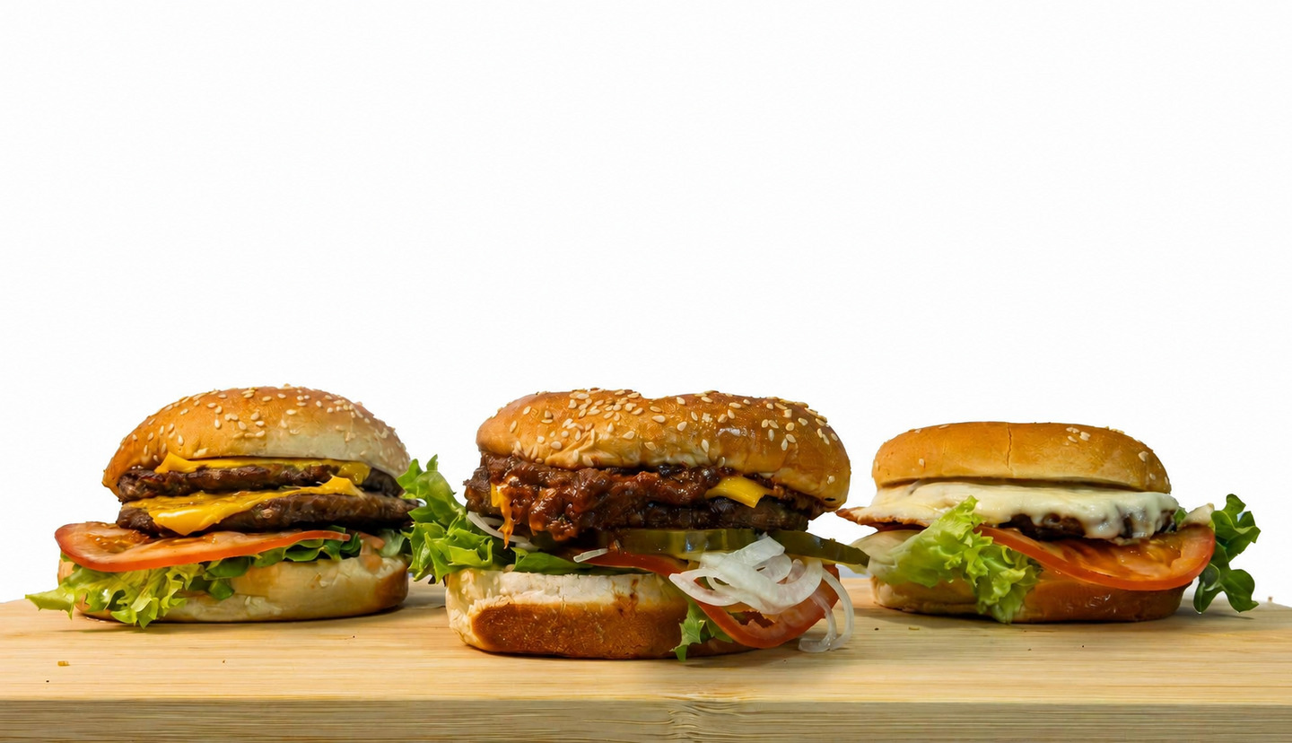 Three different Salty’s burgers on a wooden counter